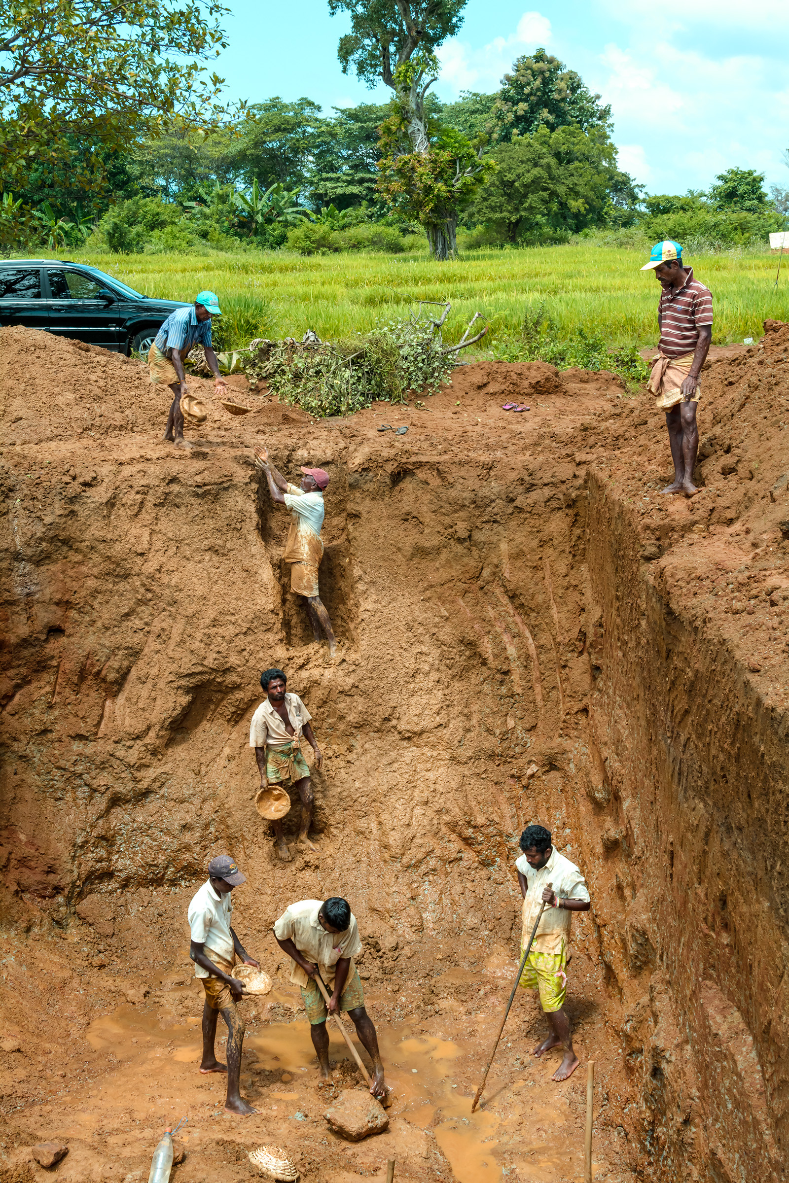 Most of the gemstone mining in Sri Lanka is pit mining using hand-powered techniques. At this larger pit, miners toss the gravel up in baskets.